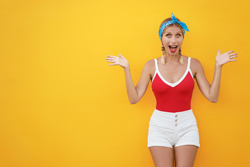 Wow! Shock! Expressing joy! Happy pretty young woman in shorts. Yellow wall background.