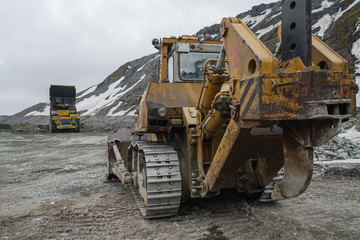 Powerful quarry bulldozer and gigat dump truck operating in the apatite mine in the Murmansk region.