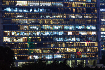 Fototapeta na wymiar Office building exterior in the late evening with interior lights. Business people working in the evening. Illuminated office building