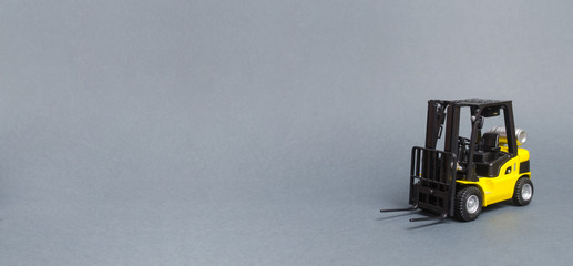 Yellow forklift truck on gray background. Warehouse equipment, vehicle. Logistics and transport infrastructure, industry and agriculture. Unloading, transportation, sorting. Banner, copy space © Andrii Yalanskyi