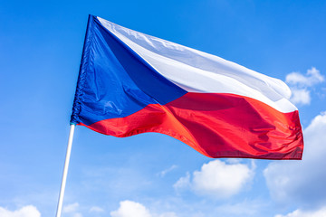 The national flag of Czech republic. National flag of Czechia. Close up shot of a flag on a blue  sky background. Czech flag waving in the wind.