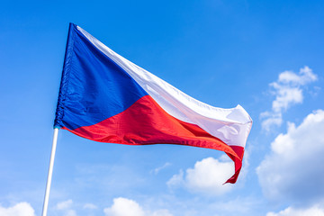 The national flag of Czech republic. National flag of Czechia. Close up shot of a flag on a blue  sky background. Czech flag waving in the wind.