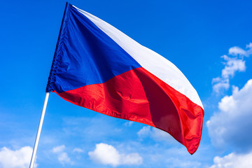 The national flag of Czech republic. National flag of Czechia. Close up shot of a flag on a blue  sky background. Czech flag waving in the wind.