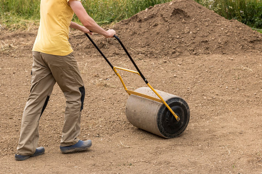 A man with a soil roller at work - Powered by Adobe