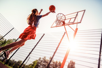Long-haired pretty girl doing sport on a basketball playground