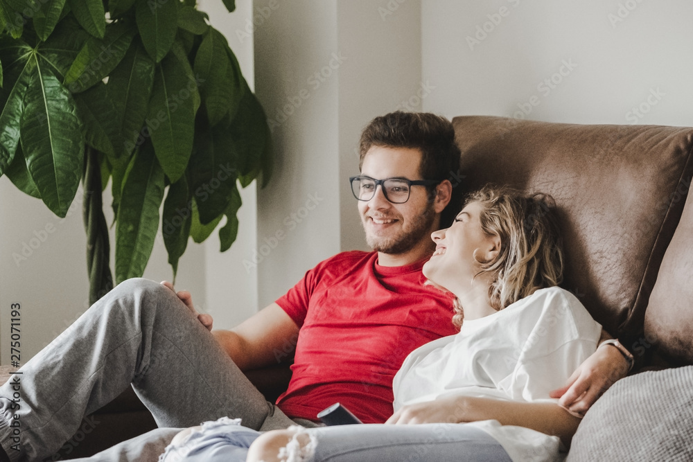 Wall mural a young couple watches television on the couch at home