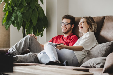 A young couple watches television on the couch at home