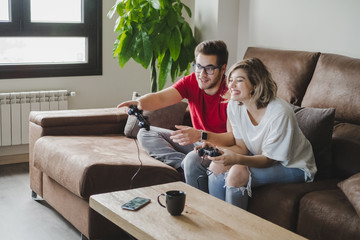 Young couple plays a video game with the console on the couch at home