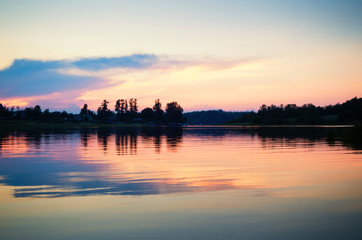 Fototapeta na wymiar Beautiful golden sunset on a lake. Black silhouetter of trees on the lake shore. Peaceful time at dusk.