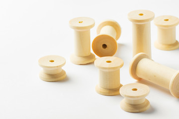 Variety of wooden thread spools of different sizes scattered on white background. Sewing crafts hobbies tailoring fashion clothes making concept. Eco nature friendly reusable materials. Zero waste