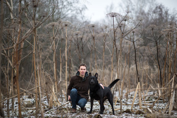 A man with a mongrel dog walking on a winter meadow