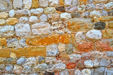 background of many rough colored stones of the old wall