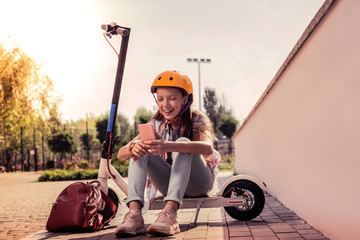Laughing pretty girl sitting on her new electronic scooter