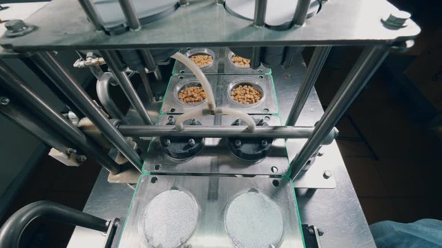 Industrial mechanism is putting foil onto plates with bread crumbs