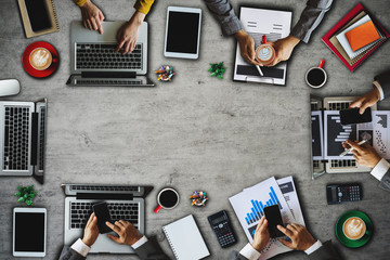 Top view of businessman Group of Multiethnic Busy People meeting with other in modern office with laptop computer, smartphone, tablet, coffee and document on table.