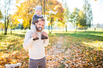 Funny man with baby pacifier in his mouse. Young father sucks  baby nipple and holding child on his...