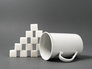 refined sugar lump white and white cup on a gray background