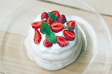Pavlova Meringue dessert on white plate, top view. This is dessert made of round meringue and strawberry on top.