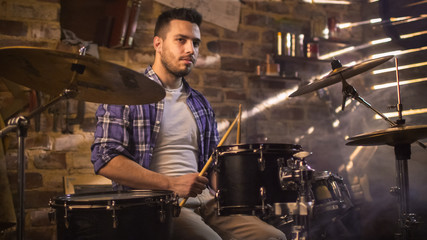 Drummer plays music while rehearsing a song in a home studio in a garage.