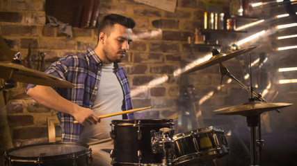 Drummer plays music while rehearsing a song in a home studio in a garage.