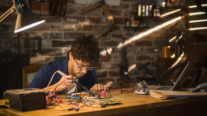 Student is studying electronics and soldering a circuit board in a garage.