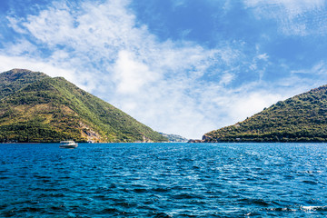 Single boat over the blue calm lake near the green mountain