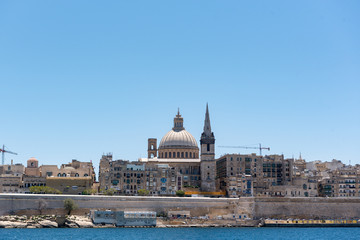 Fototapeta na wymiar Beautiful Valletta skyline under blue sky, Valletta to Sliema Ferry, viewed from Manoel Island across Marsamxett Harbour. Valletta, Capital city of Malta, November 2019