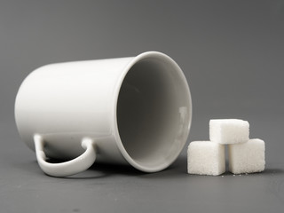refined sugar lump white and white cup on a gray background