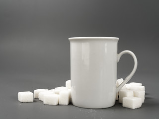 refined sugar lump white and white cup on a gray background