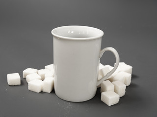 refined sugar lump white and white cup on a gray background