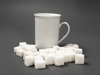 refined sugar lump white and white cup on a gray background