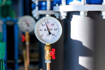 Closeup of manometer, measuring gas pressure. Pipes and valves at industrial plant. Pressure gauge,...
