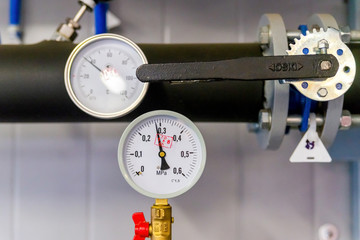 Closeup of manometer, measuring gas pressure. Pipes and valves at industrial plant. Pressure gauge, measuring instrument close up on hot water, oil or gas pipeline