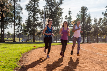 Fototapeta premium Three young women running on the running track