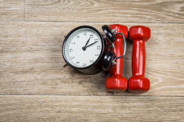 Time for exercising concept. Clock and dumbbell
