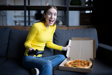 Funny brunette girl in yellow sweater eating pizza at home. Pizza delivery
