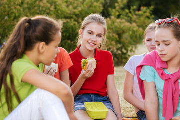 Friends sitting on the grass eating healthy food at a lunch