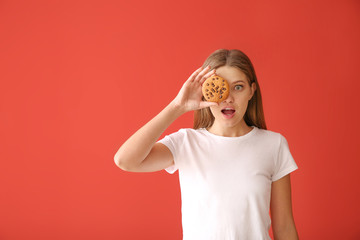 Emotional young woman with tasty cookie on color background
