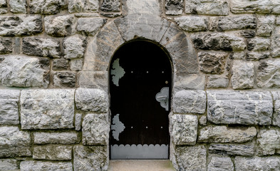 massive wooden door in a stone wall made of large granite blocks