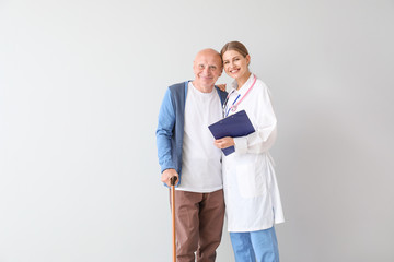 Elderly man with doctor on light background