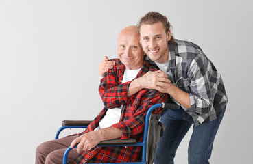 Fototapeta na wymiar Elderly man with his son on light background