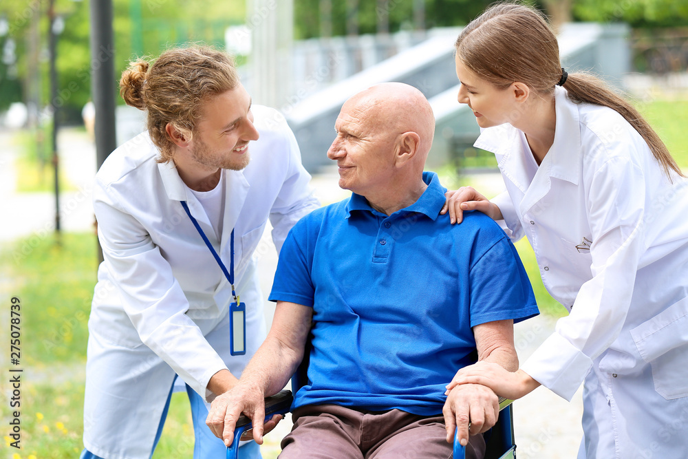 Poster Elderly man with caregivers in park