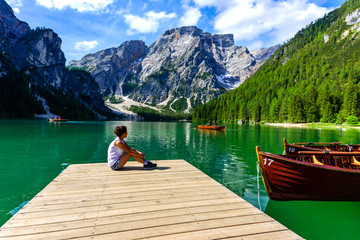Woman relaxing on Pier at Lake Braies also known as Pragser Wildsee  in beautiful mountain scenery. Amazing Travel destination Lago di Braies in Dolomites, South Tyrol, Italy, Europe.