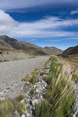 gravel road cutting through empty high alpine grasslands