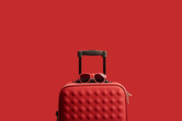red colorful textured travel bag with sunglasses isolated on red