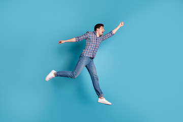 Full length body size view photo of frightened millennial hold hand hang hanger scream shout wind blows dressed fashionable checkered clothing denim sneakers isolated on blue background