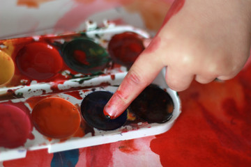photo child draws touches the finger with watercolor honey paint.