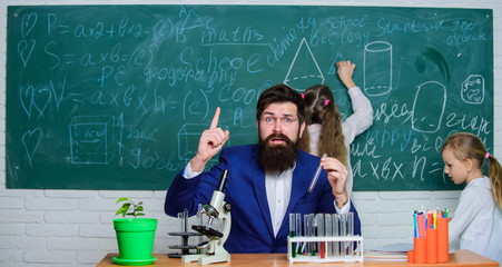 Man bearded teacher work with microscope and test tubes in biology classroom. School teacher of...