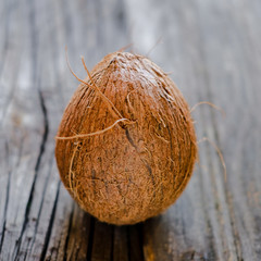 Whole hairy brown coconut on wooden background.