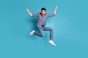 Full length body size view photo cute nice youth raise fists scream yeah celebration wonderful news thrilled satisfied candid checked shirt jeans sneakers weekend holidays isolated blue background